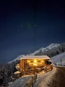 a house covered in lights in the snow at night at Das Grünholz Aparthotel in Mühlbach am Hochkönig