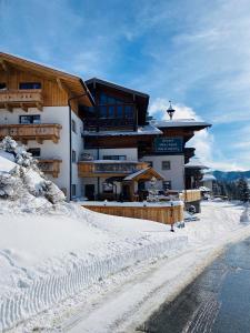 a large building in the snow in front of a road at Das Grünholz Aparthotel in Mühlbach am Hochkönig