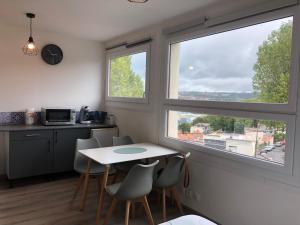 eine Küche mit einem Tisch und Stühlen sowie 2 Fenstern in der Unterkunft Studio - Parking privé - Wifi - proche Nausicaa et plage in Le Portel