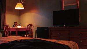 1 dormitorio con TV y tocador con mesa en Hôtel Val-des-Sources, en Asbestos