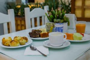 a table with plates of pastries and a cup of coffee at Hotel San Gabriel in São Paulo