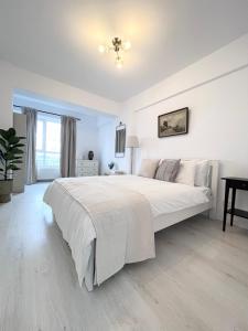 a white bedroom with a large bed and a table at Apartament Vivo & Pool access - Free parking in Constanţa