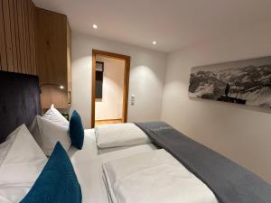 ein Schlafzimmer mit einem großen weißen Bett mit blauen Kissen in der Unterkunft Ferienwohnungen Kohler komplett neu renoviert E-Ladestaion kostenlos in Mittelberg