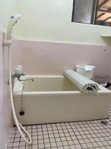 ein Badezimmer mit einer Badewanne mit einem Schlauch in der Unterkunft Yoka House - Vacation STAY 46247v in Tokunoshima