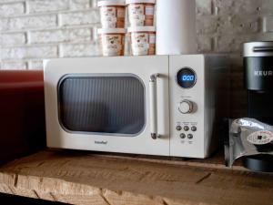 a microwave sitting on top of a wooden table at Stonegate Lodge Salt Water Pool2 Queen Beds Fire Pits Fast WiFi Room #205 in Eureka Springs