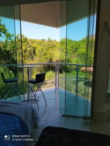a room with a glass balcony with a bed and a chair at Bangalôs Cavalcante in Cavalcante +3 photos