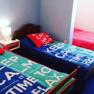 una camera con due letti e un letto rosso di Hostal San Valentín a Concepción