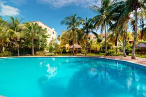 een groot zwembad met palmbomen en een gebouw bij Villas Tropical 11 in Cancun