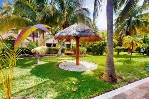 een tafel met een rieten paraplu in het gras bij Villas Tropical 11 in Cancun