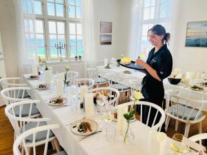 a woman holding a tray of food in a restaurant at Hotel Udsigten Marstal, Lejligheder in Marstal