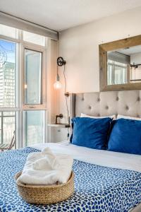 1 dormitorio con cama con almohadas azules y espejo en Beautiful Condos By CN Tower en Toronto