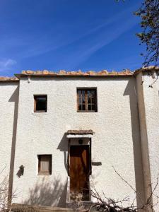 un edificio blanco con puerta y ventanas de madera en EL RINCON DE YEGEN en Yegen