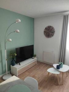 a living room with a flat screen tv and two tables at Studio Calais Front de mer-Le Cocon du Dragon-Classé 3 etoiles in Calais