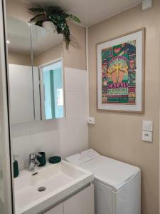 La salle de bains blanche est pourvue d'un lavabo et d'un miroir. dans l'établissement Studio Calais Front de mer-Le Cocon du Dragon-Classé 3 etoiles, à Calais