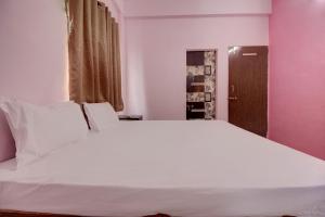 KorādihにあるSuper OYO Hotel Elite Innのピンクの壁の客室で、白い大型ベッド1台が備わります。