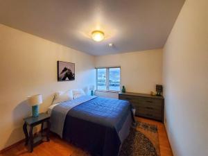 a bedroom with a blue bed and a window at Downtown Juneau Gem: 1BR Apt with Stunning Views! in Juneau