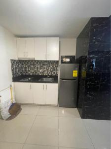 a kitchen with white cabinets and a black refrigerator at Resort-Style Living at the 'Wall Street of the Philippines' in Makati! Enjoy the epitome of luxury near NAIA Airport & BGC, FREE POOL ACCESS, WIFI, and NETFLIX. Secure Your Limited Offer This Month! in Manila