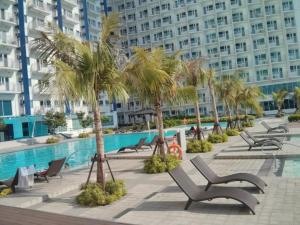 a resort with a pool and palm trees and chairs at Resort-Style Living at the 'Wall Street of the Philippines' in Makati! Enjoy the epitome of luxury near NAIA Airport & BGC, FREE POOL ACCESS, WIFI, and NETFLIX. Secure Your Limited Offer This Month! in Manila