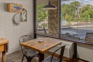 a table and chairs in a room with a window at Stonegate Lodge Pool Fire Pits King BedFast WiFi 50in TV Room #209 in Eureka Springs