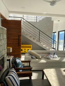 a living room with a couch and a staircase at Casa estrada da torre in Ilhabela