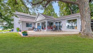 a white house with a patio and a tree at The Lakeside Lookout on Gingles Point in Arnolds Park