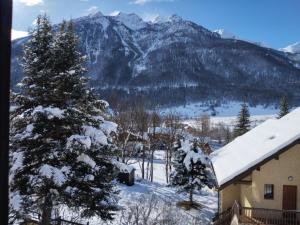una montaña cubierta de nieve con una casa y un árbol en Agréable appartement au calme avec vue montagne, commune de Le Monêtier les Bains - Le Freyssinet, en Les Guibertes