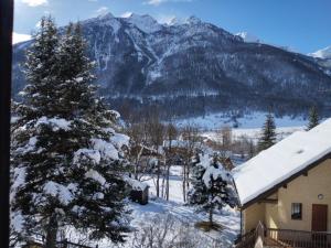 une montagne enneigée avec une maison et un arbre dans l'établissement Agréable appartement au calme avec vue montagne, commune de Le Monêtier les Bains - Le Freyssinet, à Les Guibertes