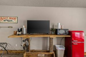 a television on a wooden table next to a refrigerator at Stonegate Lodge 2mi to Historic DTWN Pool WiFi 2 Queen Beds Room #210 in Eureka Springs