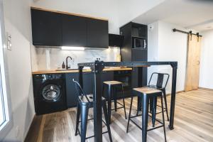 - une cuisine avec un comptoir et des tabourets dans une pièce dans l'établissement LE FACTORY aux pieds de la gare SNCF Laval, à Laval