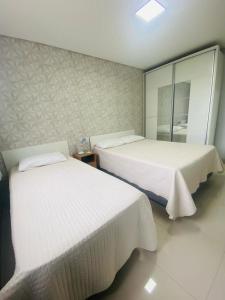 1 dormitorio con 2 camas y espejo en Residencial Mariano 4 - Vista para praia e Mar, en Florianópolis