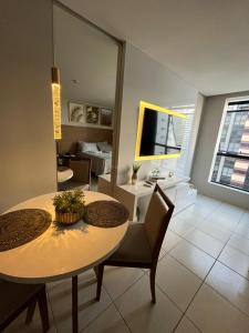 a room with a table and chairs and a living room at Suíte luxo com tela de cinema no América Towers Studio Residence in Salvador