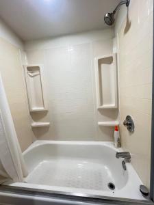 La salle de bains blanche est pourvue d'une baignoire et d'une douche. dans l'établissement Work, Rest and Play: WiFi, TV and Backyard Bliss, à North Miami Beach