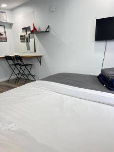 Schlafzimmer mit einem weißen Bett und einem Schreibtisch in der Unterkunft Work, Rest and Play: WiFi, TV and Backyard Bliss in North Miami Beach