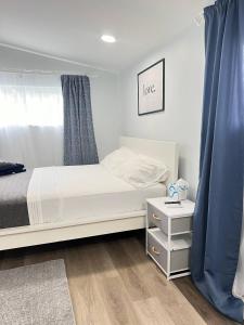 a bedroom with a white bed and a blue curtain at Work, Rest and Play: WiFi, TV and Backyard Bliss in North Miami Beach