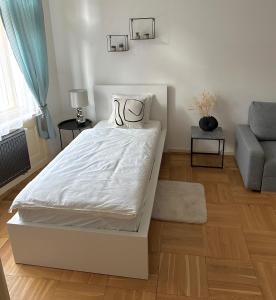 a bedroom with a white bed and a couch at Byt ve městě Praha 2 in Prague