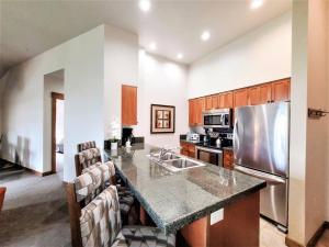 a kitchen with a counter with a sink and a refrigerator at Hyatt Main Street Station 3BD B - Steps to Peak 9 in Breckenridge
