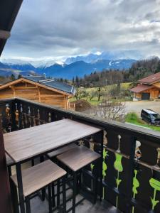 a wooden bench on a balcony with mountains in the background at Les Balcons du Mont-Blanc : Appartement centre village in Cordon