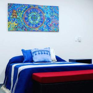 1 dormitorio con 1 cama con una pintura en la pared en Studios V19, en Colima