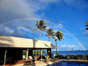 um arco-íris sobre uma piscina com cadeiras e palmeiras em Oceanfront true 2 bedroom w/lanai on Molokai em Ualapue