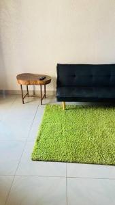 a green rug next to a black couch and a table at Independent apartment in a villa in Ouagadougou