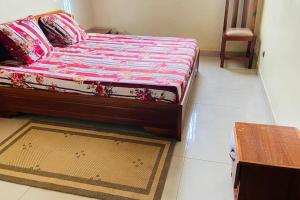 a bed in a room with a table and a floor at Independent apartment in a villa in Ouagadougou