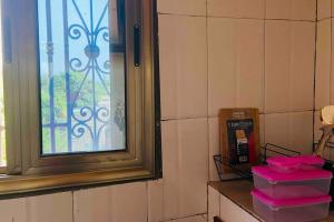 Zimmer mit Fenster und rosa Behältern auf der Theke in der Unterkunft Independent apartment in a villa in Ouagadougou