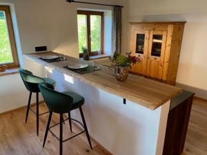 une cuisine avec un comptoir et deux tabourets au bar dans l'établissement Bergromantik Apartments Fritzenlehen, à Berchtesgaden