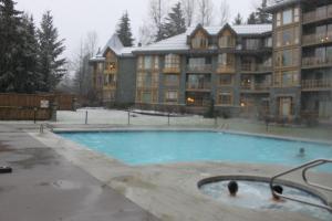 惠斯勒的住宿－Cascade Lodge suite WIFI cable HDTV pool 2 hot tubs sauna gym，一座大建筑前的游泳池