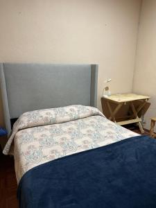 een slaapkamer met een bed met een blauwe sprei en een tafel bij Casa Yolcatl in Mexico-Stad