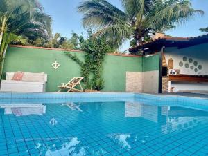 a swimming pool in front of a house with palm trees at Aconchego de geriba in Búzios