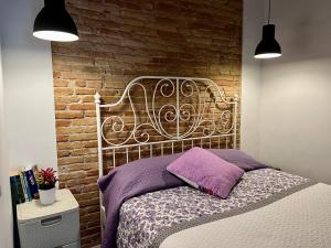 a bed in a bedroom with a brick wall at Bonito apartamento en zona centrica de Barcelona in Barcelona