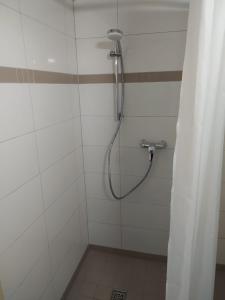 um chuveiro com uma mangueira numa casa de banho branca em Ferienwohnung in Niedraula em Niederaula
