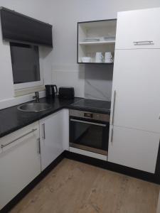 uma cozinha com armários brancos e um lavatório em Ferienwohnung in Niedraula em Niederaula