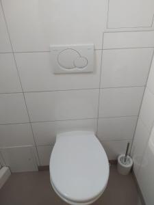 a bathroom with a white toilet in a white tiled wall at Ferienwohnung in Niedraula in Niederaula